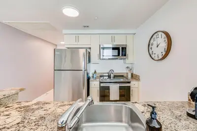 a kitchen with a stainless steel refrigerator and a clock at Bay View Beauty 1 Bedroom condo in Coconut Grove Parking Included in Miami
