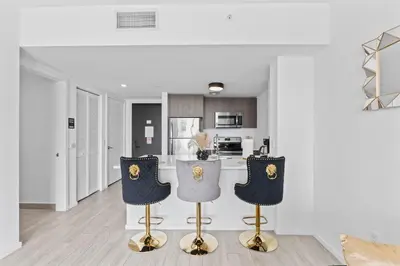 a kitchen with white walls and gold bar stools at Miami Luxury Suite Infinity Pool in Miami