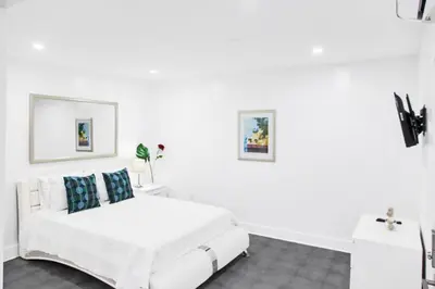 a white bedroom with a white bed and blue pillows at Miami Designer Apartment Unit 3 in Miami