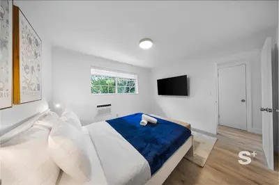 a white bedroom with a bed and a television at Modern 1-BD Miami Apt Gym, BBQ, Free Parking in Miami