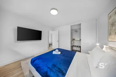 a white bedroom with a blue bed and a flat screen tv at Modern 1-BD Miami Apt Gym, BBQ, Free Parking in Miami