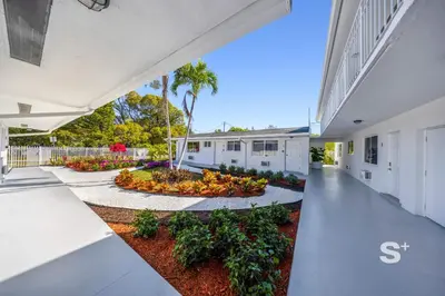 an exterior view of a white building with a courtyard at Modern 1-BD Miami Apt Gym, BBQ, Free Parking in Miami