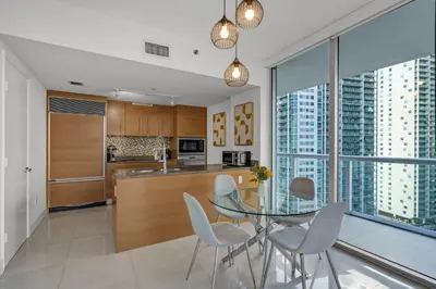 a kitchen with a glass table and white chairs at icon Brickell 2 bed 2bath at W residence in Miami