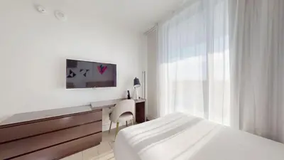 a white bedroom with a bed and a desk and a tv at Hyde Beach House 3BR2BA in Hollywood