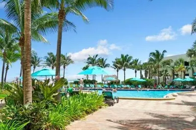 a swimming pool with palm trees and blue umbrellas at Tides Great condo on the beach Big promotions in Hollywood