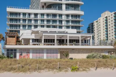 a building on the beach with buildings in the background at Beach Apt Full kitchen and King size bed in Hallandale Beach