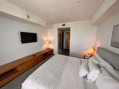 a bedroom with a white bed and a flat screen tv at Beach Apt Full kitchen and King size bed in Hallandale Beach