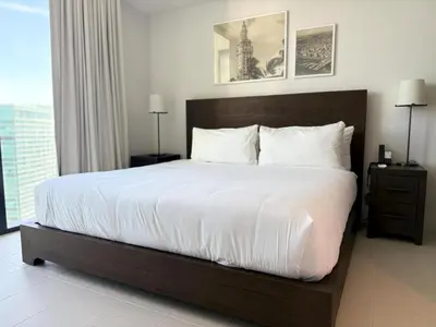 a bedroom with a large bed with white sheets at Sky-High Views Pool – Steps from Miami Arena in Miami