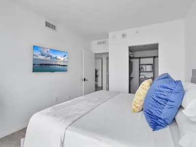 a white bedroom with a large bed with blue pillows at X Lounge V-Panoramic Private Residence in Miami