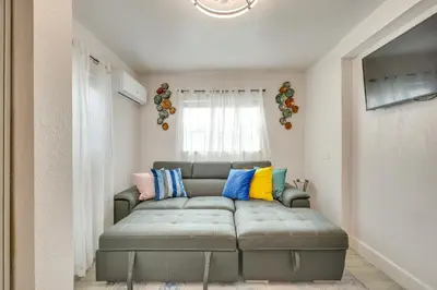 a living room with a gray couch with colorful pillows at 2 Mi to Hard Rock Stadium Studio in Miami Gardens in Miami