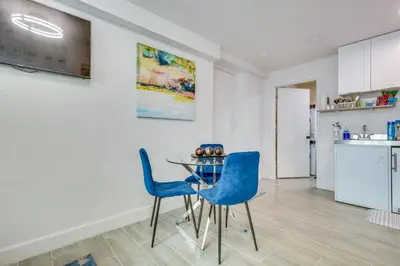 a dining room with blue chairs and a glass table at 2 Mi to Hard Rock Stadium Studio in Miami Gardens in Miami
