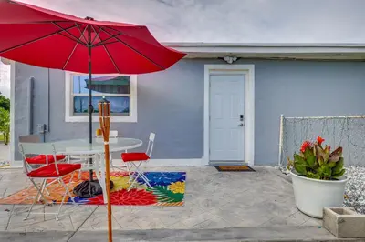 a table and chairs with a red umbrella on a patio at 2 Mi to Hard Rock Stadium Studio in Miami Gardens in Miami