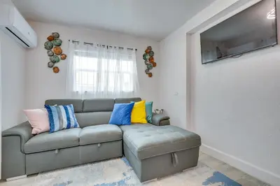 a living room with a gray couch with colorful pillows at 2 Mi to Hard Rock Stadium Studio in Miami Gardens in Miami