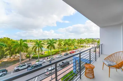 a balcony with a view of a street and palm trees at Beautiful and Stylish Condo Close The Doral Park in Miami
