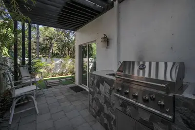 an outdoor kitchen with a stove and a chair at Grove Walk Manor 3BR Oasis in the Grove Family in Miami
