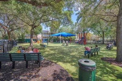 people sitting on benches in a park with a playground at Grove Walk Manor 3BR Oasis in the Grove Family in Miami
