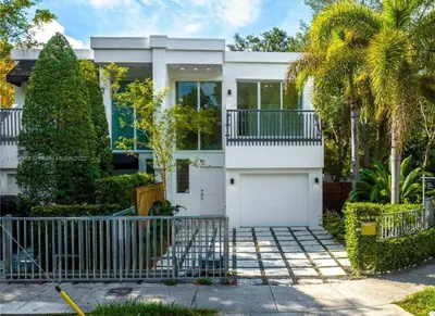 a white house with a gate and palm trees at Grove Walk Manor 3BR Oasis in the Grove Family in Miami