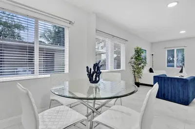 a dining room with a glass table and white chairs at Celeste House Enjoy Caribbean 2BR APT in Miami