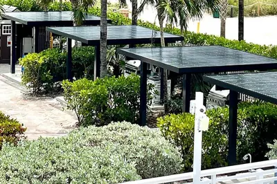 two picnic tables in a park with trees and bushes at Solara Surfside in Miami Beach