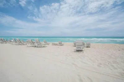 a group of lawn chairs on the beach at Solara Surfside in Miami Beach