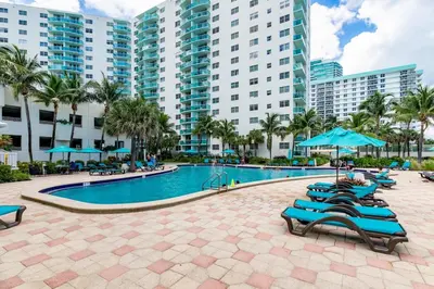 a pool at a resort with blue chairs and umbrellas at Hollywood Beachfront Retreat in Hollywood