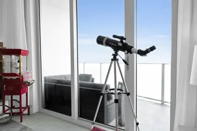 a telescope on a tripod in front of a window at Ventur Luxe Condo - Oceanview - Gym, Beach Access in Hollywood