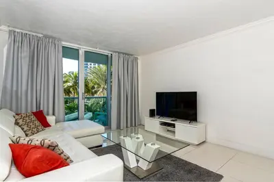 a living room with a white couch and a television at Direct access to the beach, pool and parking 3T in Hollywood