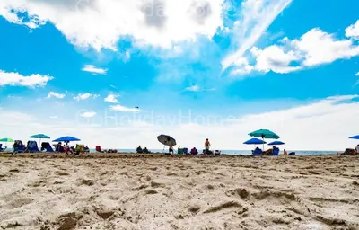 a group of people sitting under umbrellas on a beach at Direct access to the beach, pool and parking 3T in Hollywood