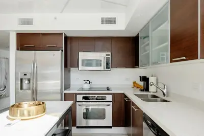 a kitchen with stainless steel appliances and wooden cabinets at LOFT Brickell River 10 min To South Beach in Miami