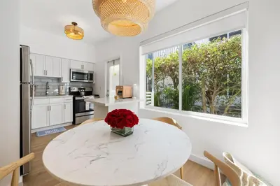 a kitchen with a white table with a vase of flowers on it at Lux Designer Apt 2BR and 2BA in the Heart of MIA Beach in Miami Beach