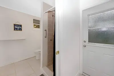 a bathroom with a shower and a toilet and a door at The Palm House in Hollywood
