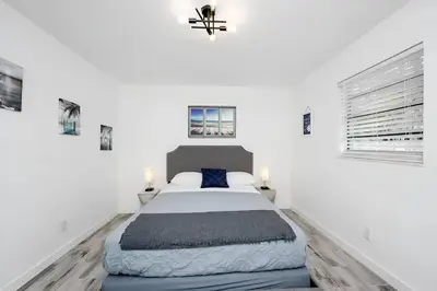 a white bedroom with a bed and two windows at Luna Beach House in Hollywood