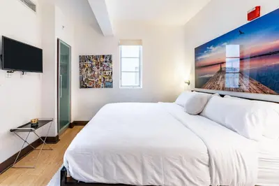 a white bedroom with a large bed and a flat screen tv at Oceanfront Oasis 2-BR Apartment on Ocean Drive in Miami Beach