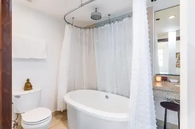 a white bathroom with a tub and a toilet at Oceanfront Oasis 2-BR Apartment on Ocean Drive in Miami Beach