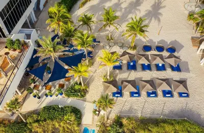 an aerial view of a resort with palm trees and blue umbrellas at 2b 2b Beautiful Apmt in Hallandale Beach with beach service in Hallandale Beach