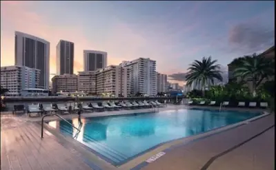 a large swimming pool with chairs and a city at 2b 2b Beautiful Apmt in Hallandale Beach with beach service in Hallandale Beach