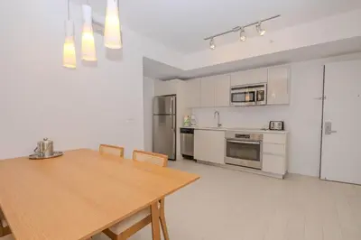 a kitchen with a wooden table and a kitchen with appliances at Steps from the beach 2B 2B Pool, Gym, and More in Hallandale Beach