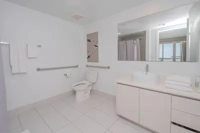 a white bathroom with a toilet and a sink at Steps from the beach 2B 2B Pool, Gym, and More in Hallandale Beach