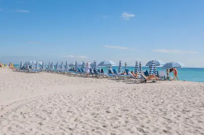 a group of chairs and umbrellas on a beach at Apartment in Miami Beach with Kitchen, Beach Service and Gym in Hallandale Beach