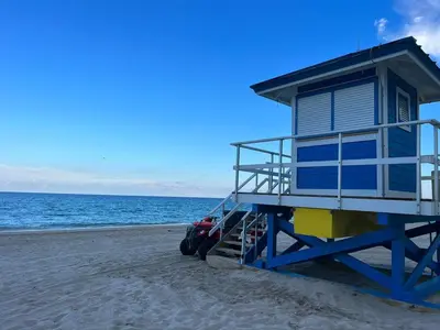 a lifeguard house on the beach with a car parked next to it at Beachfront Apt with Pool by the Ocean in Hallandale Beach
