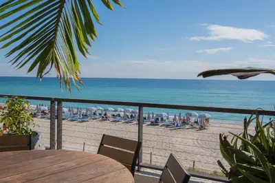 a view of a beach with a wooden table and chairs at Beachfront Apt with Pool by the Ocean in Hallandale Beach