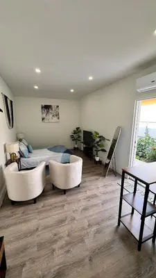 a bedroom with a bed and two white chairs at Miami North Beach in North Miami Beach