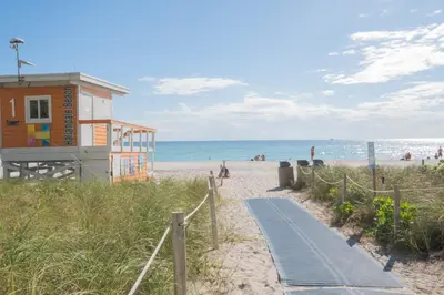 a beach with a building and a path to the beach at Beautiful studio in Beachwalk 2QB in Hallandale Beach