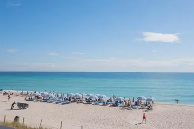a group of people on a beach with chairs and umbrellas at Beautiful Studio in Hallandale with Beach & Pool in Hallandale Beach