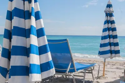 two beach chairs and umbrellas on the beach at Miami Apartment 2 full size beds & Beach Service in Hallandale Beach
