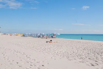 a group of people on a beach with an umbrella at BeachWalk Studio Apmt 2 Beds w Beach Service in Hallandale Beach