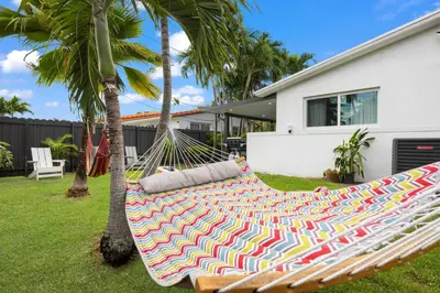 a hammock in a yard next to a house at 2BR, Families, Pets, Medical Stays, Hot Tub in Miami