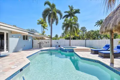 a swimming pool with blue chairs and a fence at Blue Wave Retreat at Hollywood Beach home in Hollywood