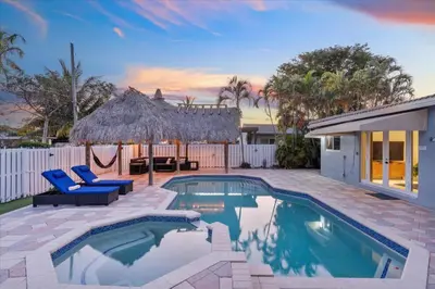 a swimming pool with two blue chairs and a house at Blue Wave Retreat at Hollywood Beach home in Hollywood
