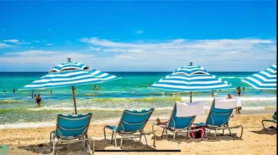 a group of chairs and umbrellas on a beach at Miami Beach 1B 1B w Kitchen and Beach Service in Hallandale Beach